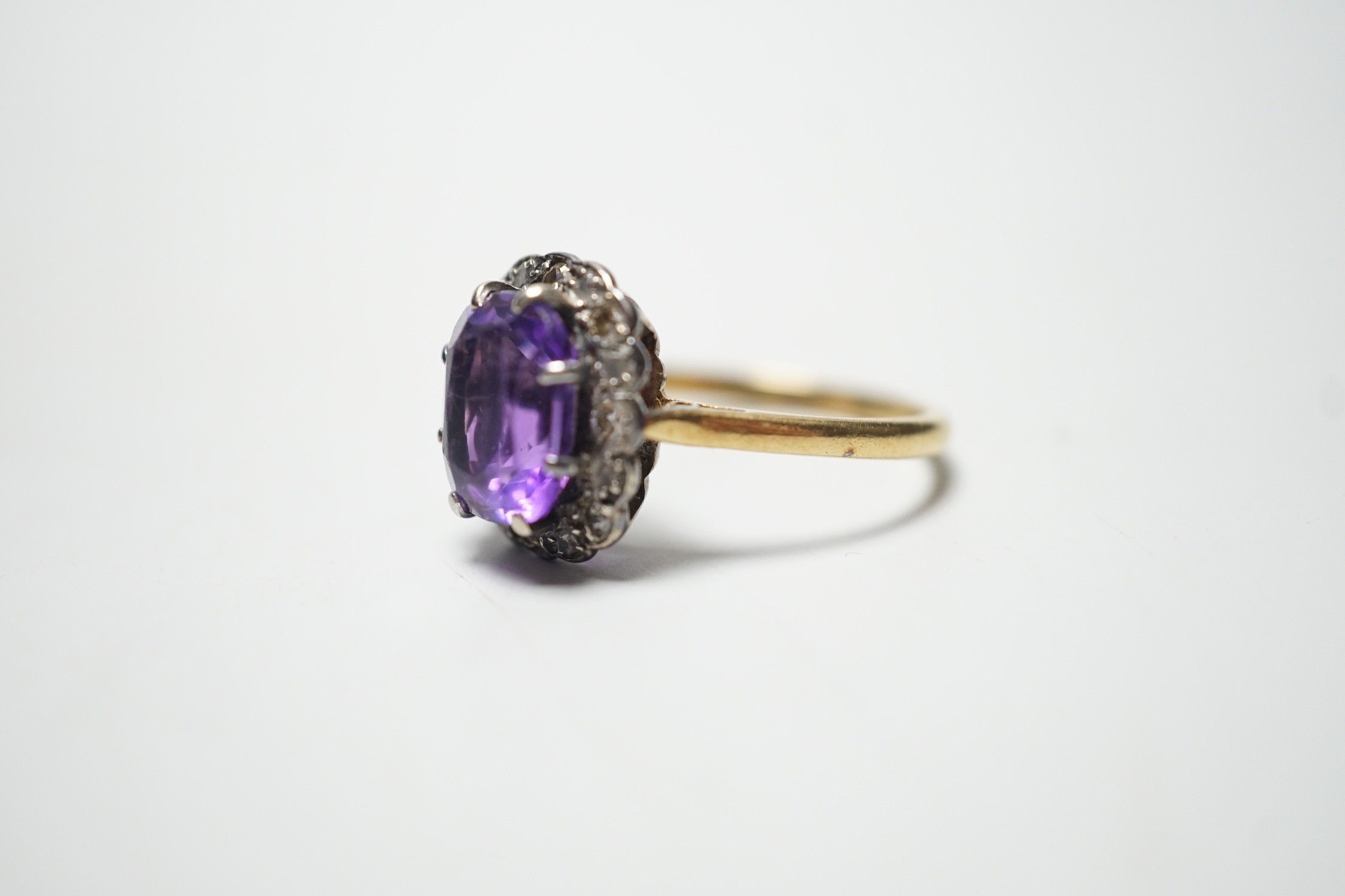 An 18ct, amethyst and diamond set oval cluster ring, size P, gross weight 4.5 grams.